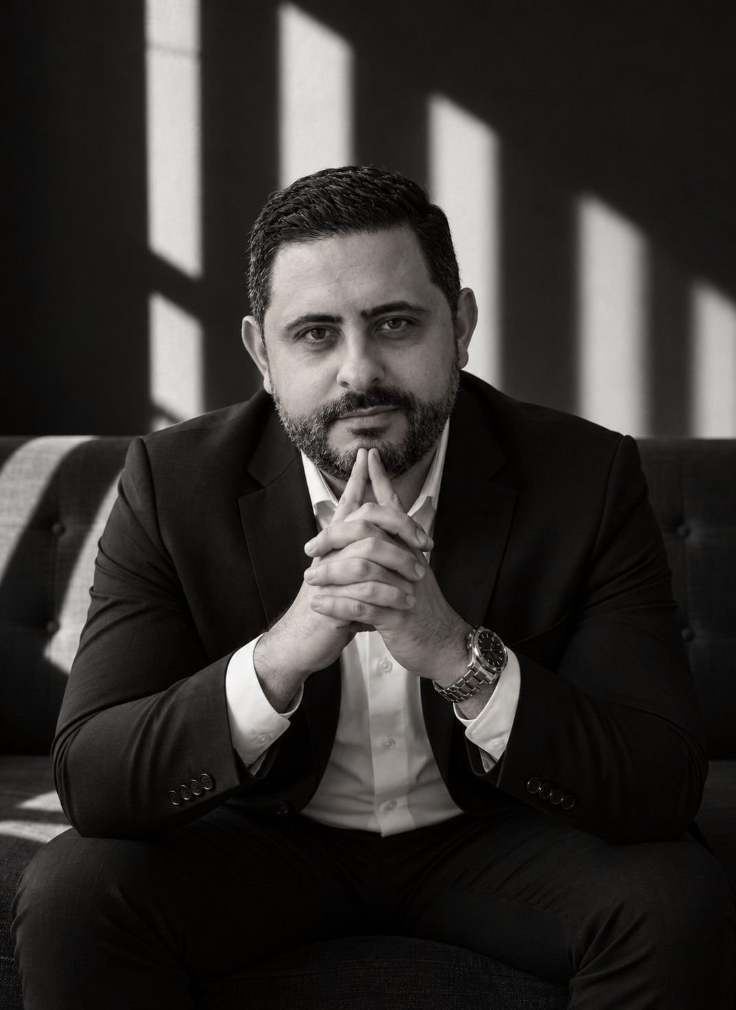Dr. Isaac Mello sentado, mãos unidas, em retrato em preto e branco