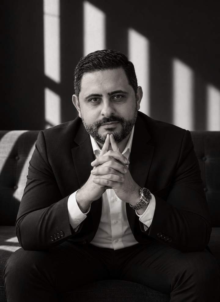 Dr. Isaac Mello sentado, mãos unidas, em retrato em preto e branco